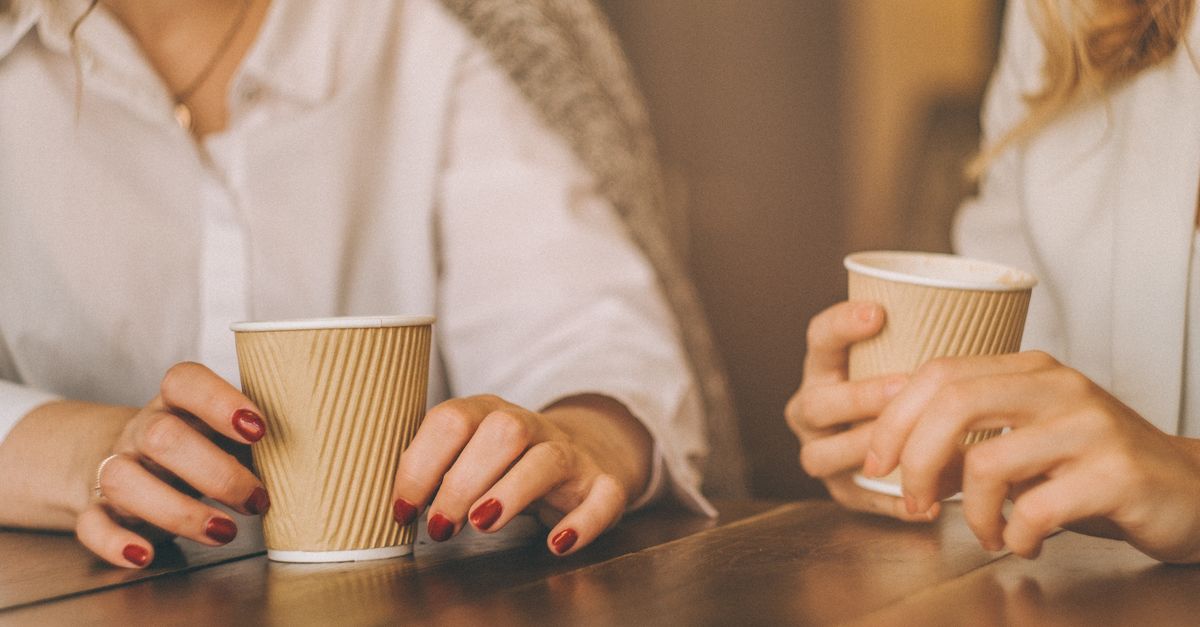 People talking around a table with cups and notebooks