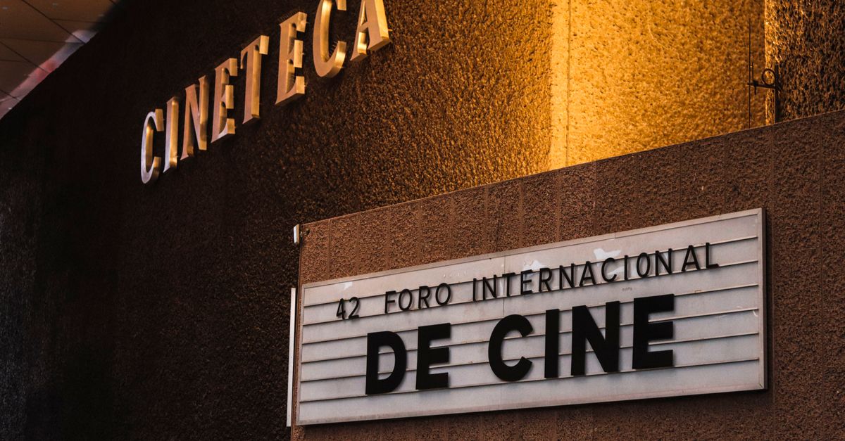 Sala de cine con butacas rojas y pantalla iluminada al fondo