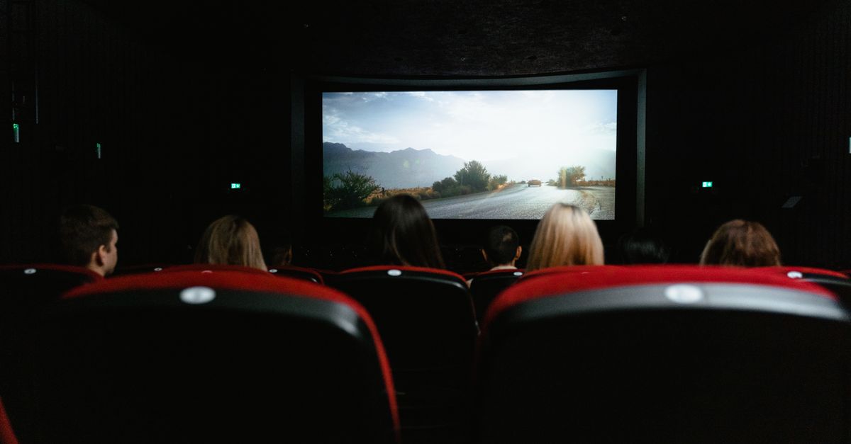Movie theater with red seats and a lit screen in the background